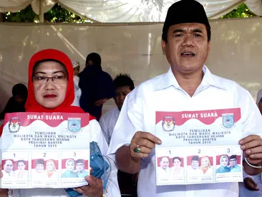 Calon Walikota Tangerang Selatan nomor urut 2 Arsid beserta istri menunjukan surat suara  di TPS 31 Kelurahan Pondok Benda, Tangsel, Rabu (9/12). Calon Walikota Tangerang Selatan ini merupakan pemilih perdana pada TPS tersebut. (Liputan6.com/Fery Pradolo)