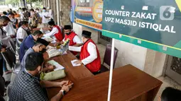 Umat muslim membayar zakat fitrah kepada amil zakat di Masjid Istiqlal, Jakarta, Jumat (7/5/2021). Panitia Zakat Masjid Istiqlal mulai membuka layanan pembayaran zakat fitrah dengan pembayaran senilai Rp 50 ribu atau 3,5 liter beras. (Liputan6.com/Faizal Fanani)