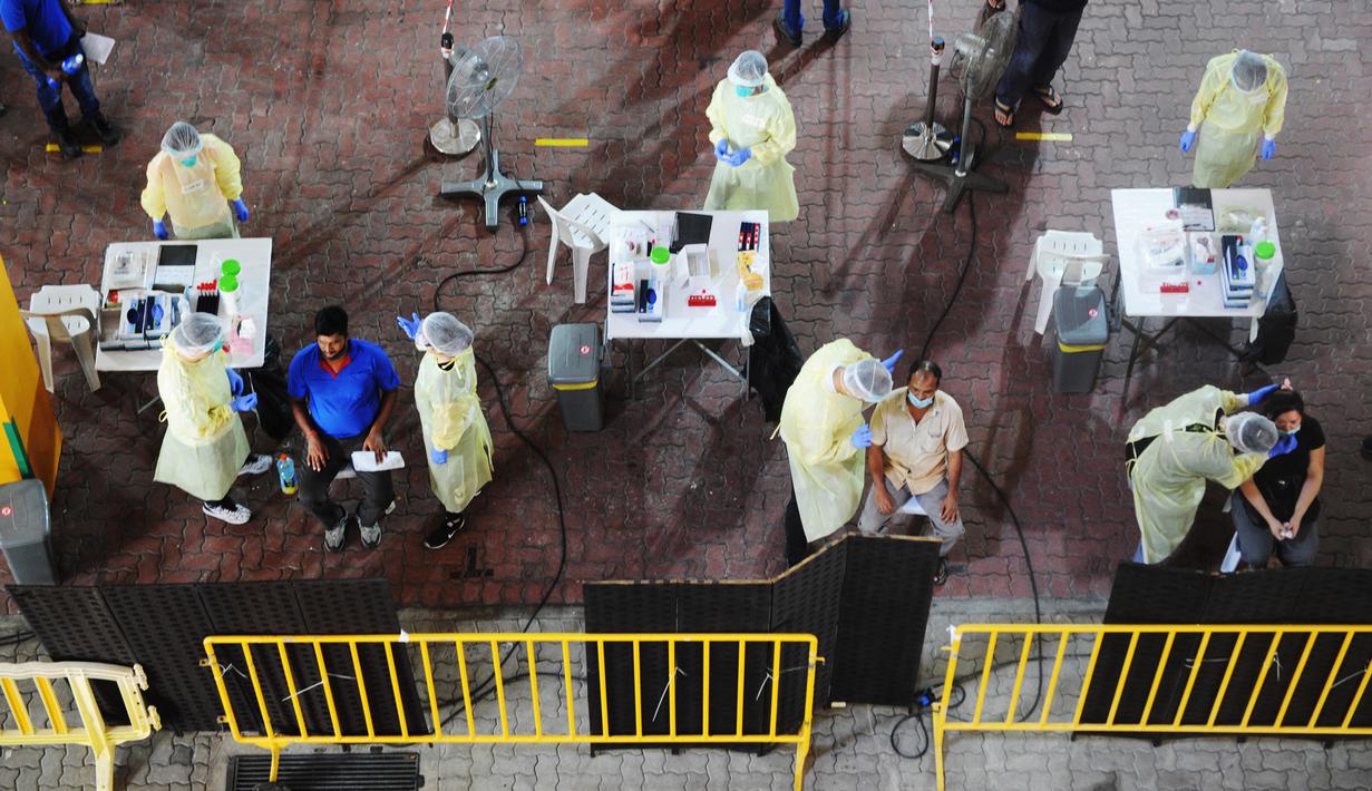 Petugas kesehatan mengumpulkan sampel usap (swab) untuk pengujian COVID-19 dari para pekerja yang siap kembali bekerja di pusat penapisan (screening) regional di Singapura (10/6/2020). (Xinhua/Then Chih Wey)