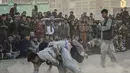 Pria Afghanistan bergulat di latar belakang selama tontonan gulat mingguan yang diadakan di arena darurat di taman Chaman-e-Hozori, di Kota Kabul (12/11/2021). (AFP/Hector Retamal)