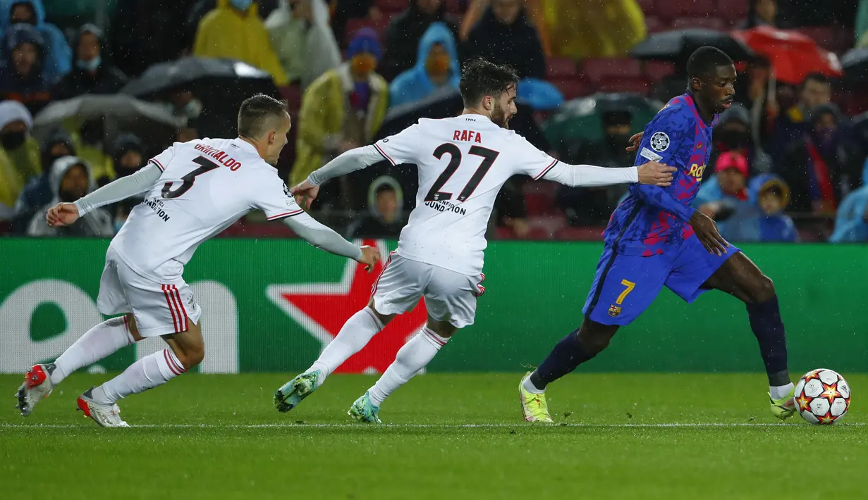 Penyerang Barcelona Ousmane Dembele berebut bola dengan pemain Benfica Rafa Silva dan Alex Grimaldo pada matchday kelima Grup E Liga Champions di Camp Nou, Rabu (24/11/2021) dini hari WIB. Barcelona hanya mampu bermain imbang 0-0 kala menjamu Benfica. (AP Photo/Joan Monfort)