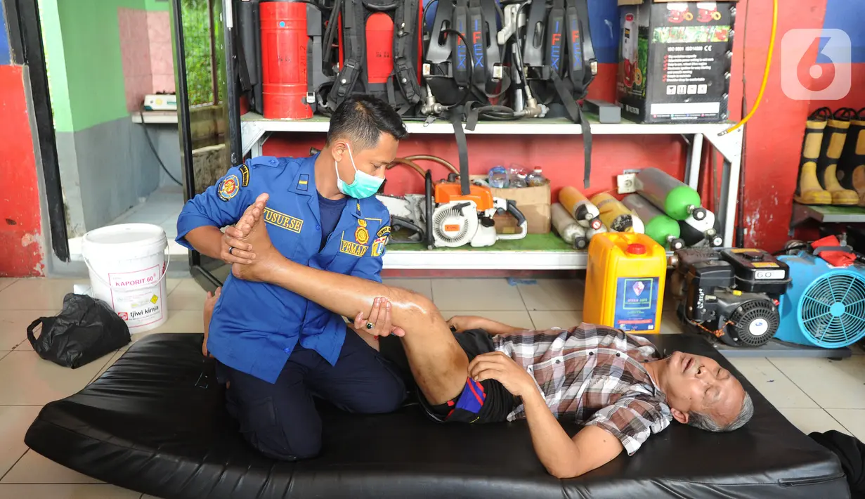 Seorang warga saat dipijat oleh petugas Damkar di Pos Damkar Ciganjur, Jagakarsa, Jakarta Selatan, Rabu (02/12/2020). Petugas Damkar memijat khas Cimande dengan bayaran seikhlasnya, pengobatan dilakukan di sela waktu senggang petugas Damkar. (merdeka.com/Arie Basuki)