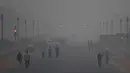 Pejalan kaki berjalan di tengah-tengah kondisi kabut asap tebal di New Delhi (2/11). Tingkat kabut melonjak selama musim dingin di Delhi, ketika kualitas udara melampaui tingkat aman Organisasi Kesehatan Dunia. (AP Photo/Money Sharma)