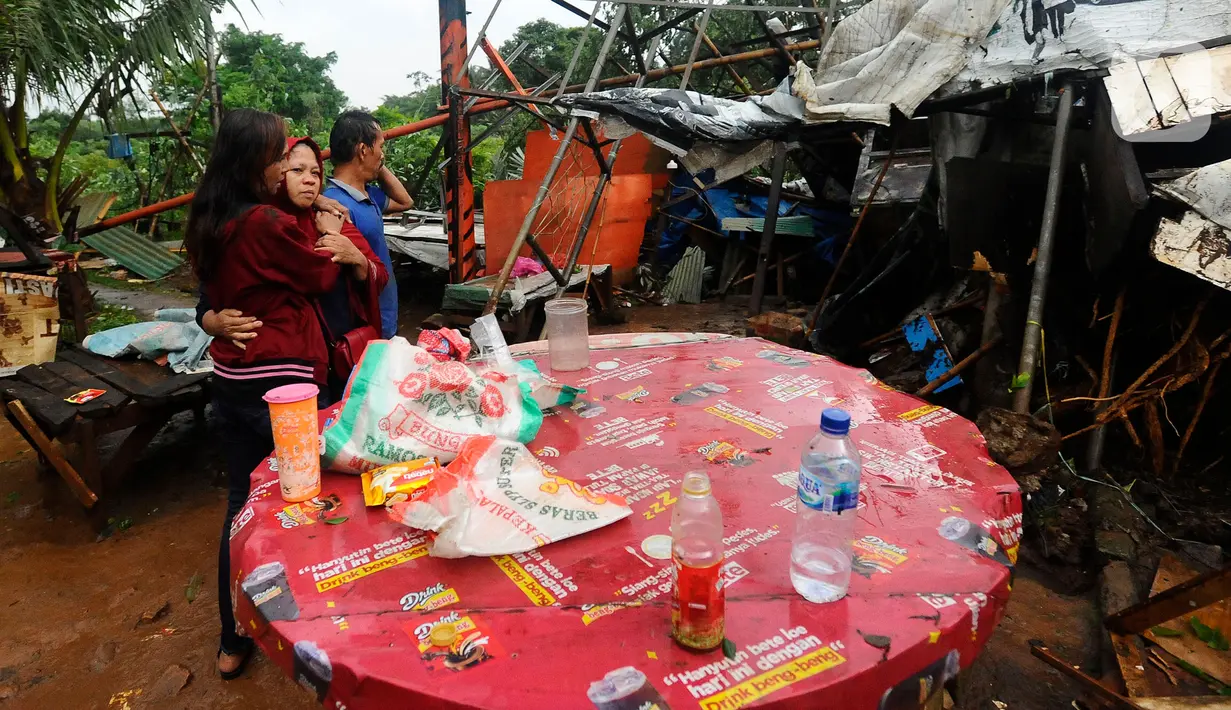 Seorang pedagang menangis usai warung kopi miliknya hancur tertimpa pohon tumbang di pinggir Jalan Raya Sawangan Depok, Minggu (09/10/20222). Setelah hujan es disertai angin kencang , banyak rumah warga yang bocor, angin kencang menumbangkan pohon-pohon besar di jalan Hingga memacetkan jalan. (merdeka.com/Arie Basuki)