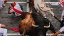 Pengunjung berlari di samping banteng-banteng petarung Victoriano del Río selama acara lari banteng ketiga di festival San Fermín di Pamplona, Spanyol, Kamis, 9 Juli 2026. (AP Photo/Miguel Oses)