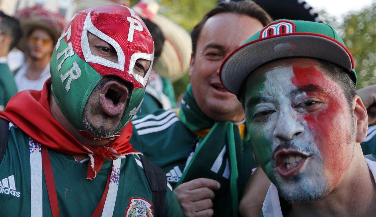 Suporter Meksiko menggunakan topeng saat merayakan kemenangan timnya atas Jerman pada laga grup F Piala Dunia 2018 di Luzhniki Stadium, Moskow, (17/6/2018). Meksiko menang 1-0. (AP/Alexander Zemlianichenko)