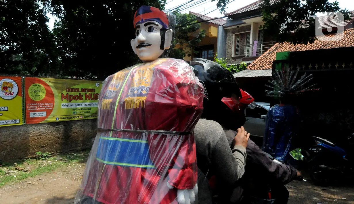 Pembeli membawa ondel-ondel di Rumah Produksi Ondel-Ondel Jakarta, Setu Babakan, Jakarta Selatan, Minggu (19/9/2021). Ondel-ondel dijual dengan harga Rp 35 ribu hingga Rp 7 juta per pasang. (merdeka.com/Arie Basuki)