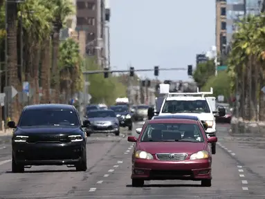 Gelombang panas naik dari trotoar saat kendaraan melaju di sepanjang jalan pusat kota saat suhu diperkirakan mencapai 115 derajat Fahrenheit di Phoenix, Selasa, 18 Juli 2023. (AP Photo/Ross D. Franklin)