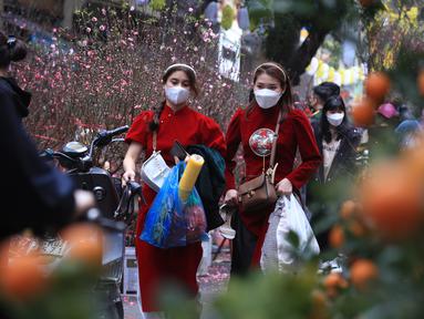 Dua wanita berbelanja di pasar "Tet" Tahun Baru Imlek tradisional di kawasan tua Hanoi, Vietnam, Jumat (28/1/2022). Vietnam merayakan Tahun Baru Imlek yang akan datang di tengah peringatan terhadap perjalanan dan pertemuan besar karena COVID -19. (AP Photo/Hau Dinh)