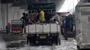 Sejumlah orang menaiki truk yang lewat untuk melalui banjir di jalan R.E Martadinata, Jakarta, Senin (6/2/2015). (Liputan6.com/Faizal Fanani)
