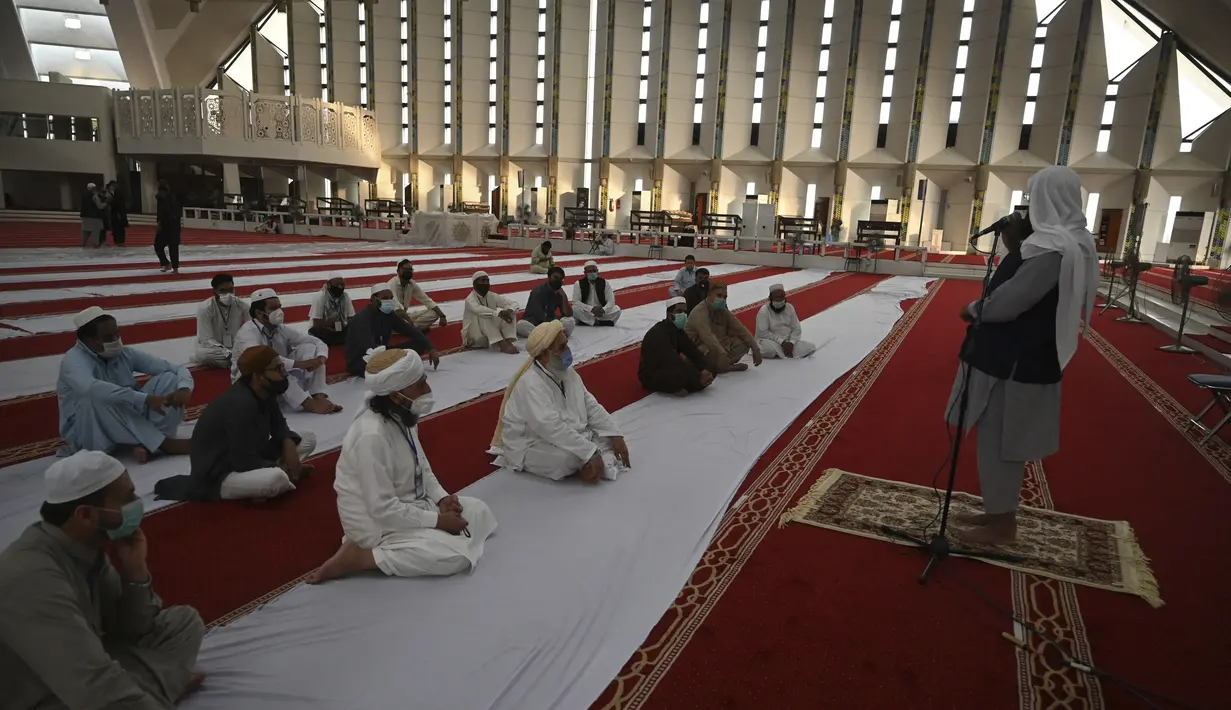 Umat Muslim mendengarkan Imam (kanan) di Masjid Agung Faisal di awal Itikaf, di sebuah masjid untuk pria selama bulan suci Ramadhan di Islamabad (3/5/2021). Umat Muslim melakukan Itikaf 10 hari terakhir bulan Ramadhan, dalam rangka meraih malam kemuliaan atau Lailatul Qadar. (AFP/Aamir Qureshi)