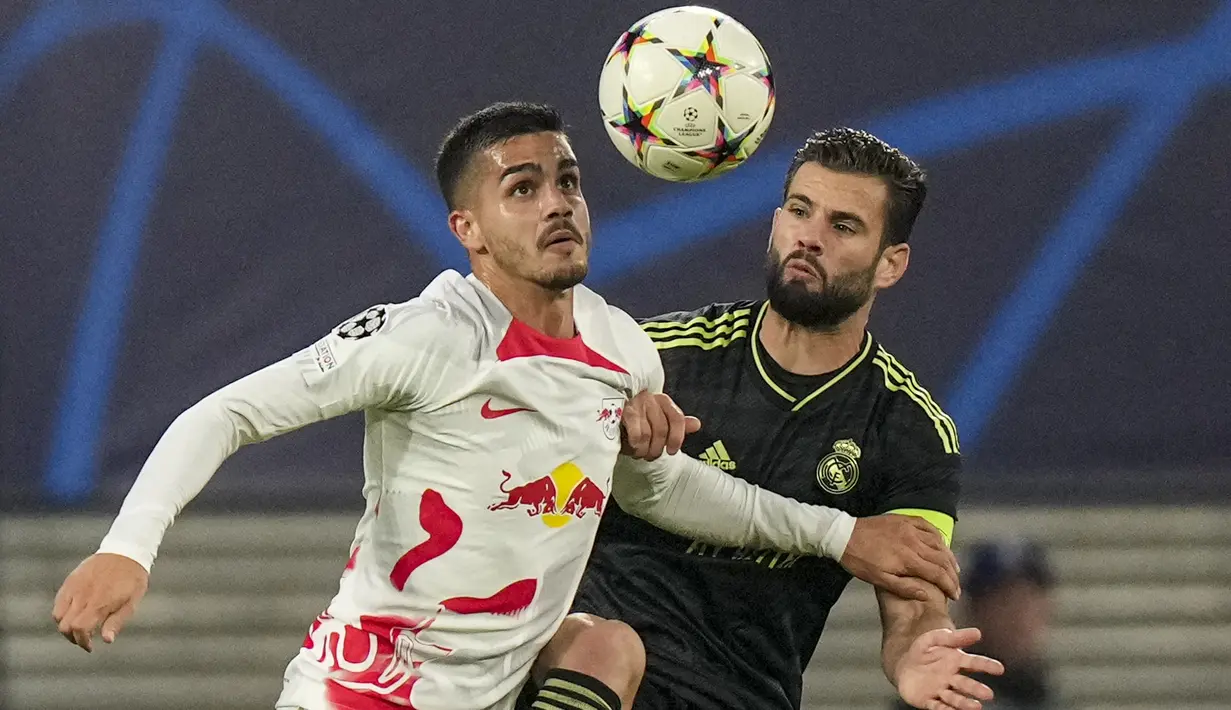 Penyerang RB Leipzig Christopher Nkunku berebut bola dengan bek Real Madrid Nacho pada pekan ke-5 Grup F Liga Champions 2022/2023 di Red Bull Arena, Rabu (26/10/2022) dinihari WIB. Dalam laga ini Madrid melesakkan 12 tembakan, sedangkan Zagreb 14 tembakan.  (AP Photo/Matthias Schrader)