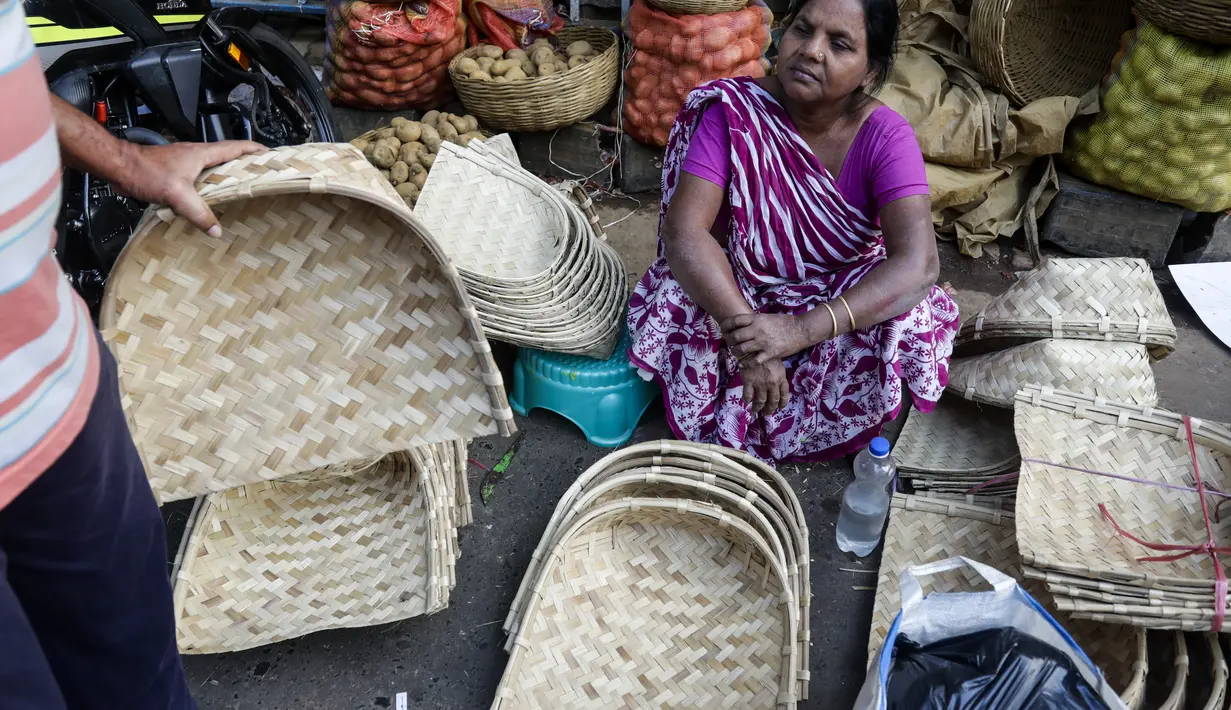 Seorang wanita menjual perlengkapan ibadah di sebuah kios pinggir jalan menjelang festival Hindu Chhath, di Kolkata, India (9/11/2021). Selama Chhath, festival Hindu kuno yang populer di kalangan kelas pekerja, ritual dilakukan untuk berterima kasih kepada Dewa Matahari. (AP Photo/Bikas Das)
