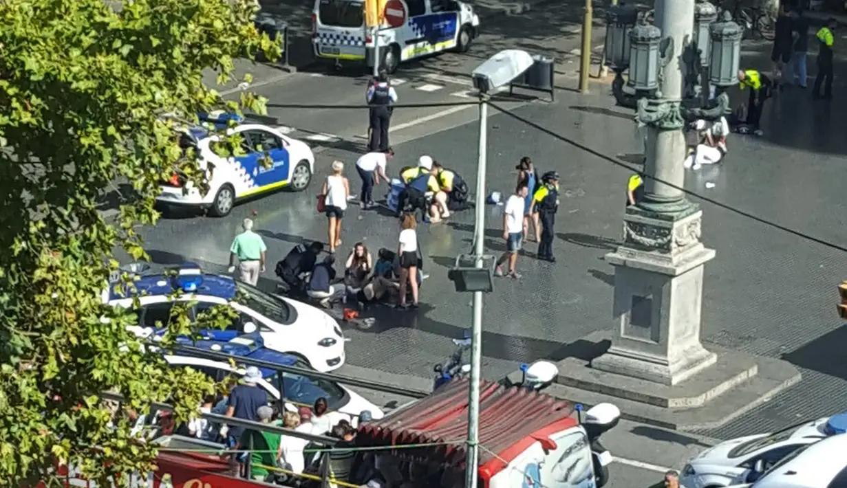 Petugas dibantu warga membantu korban setelah mobil van menabrak kerumunan orang  di Jalanan Las Ramblas, Barcelona, Spanyol (17/8). Lebih dari 50 orang dilaporkan luka-luka dan 13 orang tewas akibat kejadian tersebut. (Daniel Vil via AP)