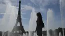 Seorang perempuan mendinginkan diri di dekat air mancur Trocadero, di tengah suhu tinggi di Paris, Kamis (16/6/2022). Prancis akan mengalami suhu yang memecahkan rekor mendekati 40 derajat Celcius pada Juni, karena gelombang panas dini yang diperkirakan akan melanda sebagian besar negara itu.
(JULIEN DE ROSA / AFP)