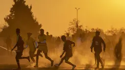 Sejumlah warga saat bermain sepak bola pada pertandingan persahabatan di lapangan yang berdebu di Soweto, Afrika Selatan, Rabu (16/6/2021).  (AP Photo/Themba Hadebe)