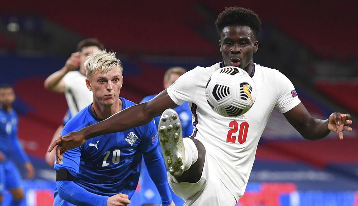 Pemain Inggris, Bukayo Saka, berebut bola dengan pemain Islandia, Albert Gudmundsson, pada laga UEFA Nations League di Stadion Wembley, Kamis (19/11/2020). Inggris menang dengan skor 4-0. (Michael Regan/Pool via AP)