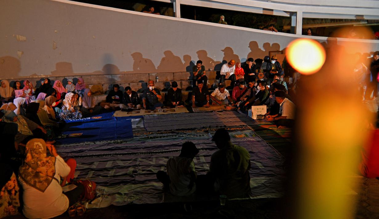 Sejumlah warga menghadiri upacara doa pada malam peringatan 17 tahun tsunami Boxing Day 2004 di monumen Kapal Tsunami Lampulo di Banda Aceh (25/12/2021). (AFP/Chaideer Mahyuddin)