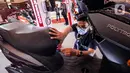 Pekerja memeriksa sepeda motor listrik yang dipamerkan pada pembukaan Indonesia Motorcycle Show (IMOS) 2022 di Jakarta Convention Center (JCC), Jakarta, Rabu (2/11/2022). IMOS 2022 memamerkan produk dan teknologi terkini industri sepeda motor Indonesia serta berbagai perlengkapan otomotif lainnya. (Liputan6.com/Johan Tallo)