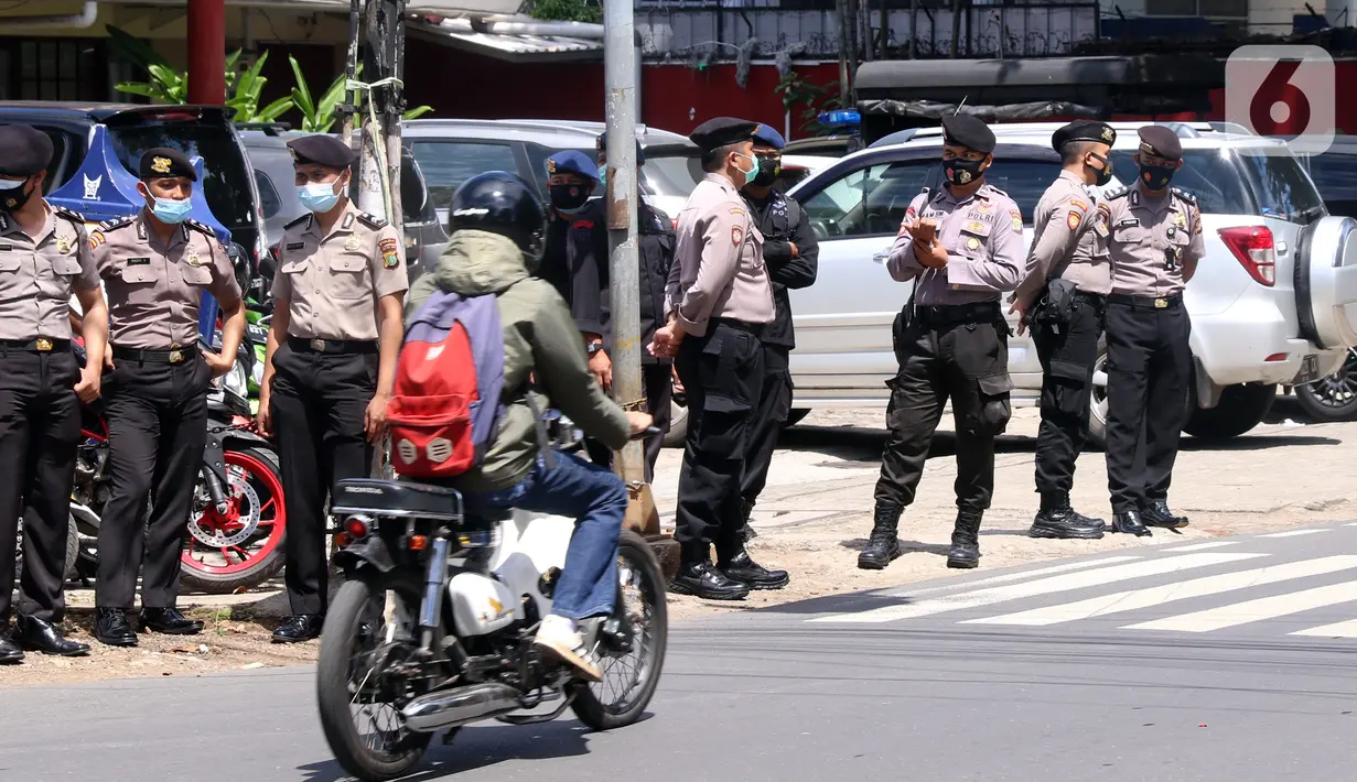 Seorang pengendara sepeda motor melintas dekat sejumlah polisi berjaga di area Pengadilan Negeri Jakarta Selatan, Senin (4/1/2021). Pengamanan ratusan aparat kepolisian dilakukan untuk mengantisipasi pergerakan masa pada saat sidang praperadilan Rizieq Shihab. (Liputan6.com/Angga Yuniar)