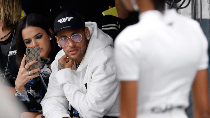 Pemain PSG, Neymar didampingi pacarnya Bruna Marquezin menghadiri acara peragaan busana Off-White Spring-Summer 2019 selama Paris Fashion Week, Prancis (27/9). Neymar tampil mengenakan jaket putih dan kaca mata emas. (AFP Photo/Francois Guillot)