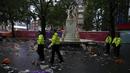 Petugas polisi berdiri di antara sampah yang ditinggalkan penggemar Skotlandia yang berpesta sebelum pertandingan grup D antara Inggris melawan Skotlandia di dekat patung William Shakespeare di Leicester Square di London, Jumat (18/6/2021). (AP Photo/Kirsty Wigglesworth)