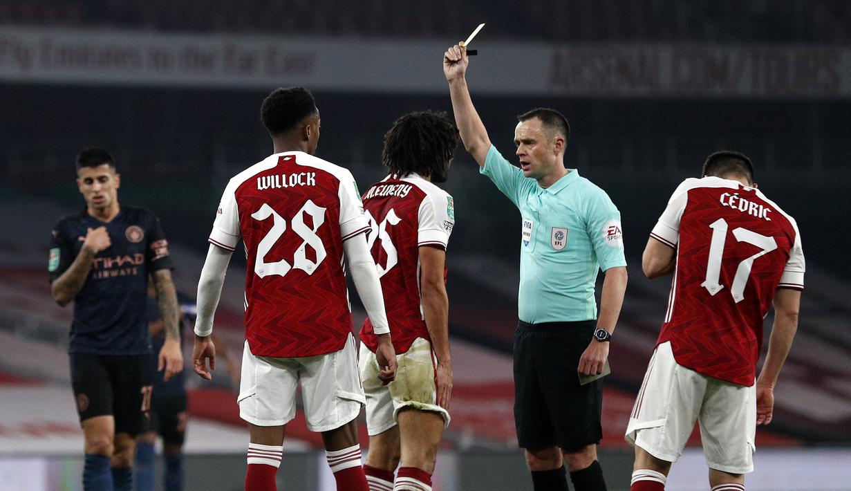 Gelandang Arsenal, Mohamed Elneny (tengah), menerima kartu kuning dari wasit Stuart Atwell dalam laga perempatfinal Piala Liga Inggris Carabao Cup melawan Manchester City di Emirates Stadium, London, Selasa (22/12/2020). Arsenal kalah 1-4 dari Manchester City. (AFP/Adrian Dennis)