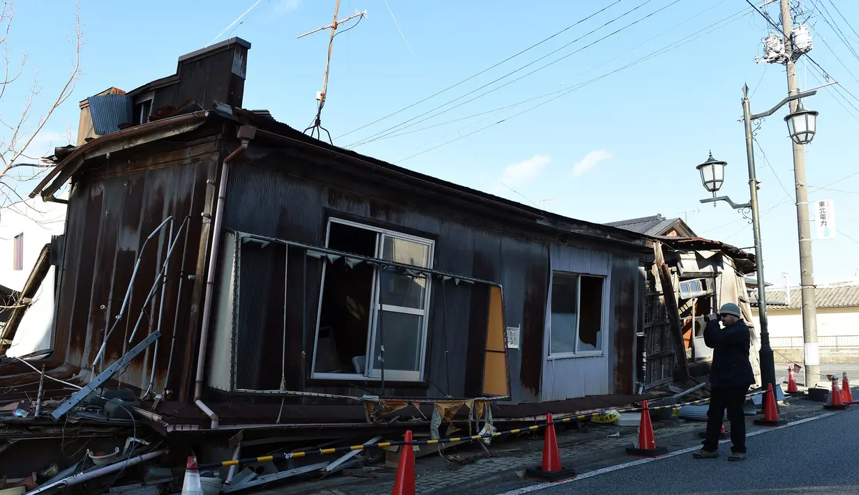 Seorang wisatawan mengamati sebuah rumah kosong di Namie, Prefektur Fukushima, 11 Februari 2016. Lima tahun pasca bencana nuklir yang dipicu gempa dan tsunami Jepang, semakin banyak wisatawan yang bergabung dengan tur Fukushima (AFP PHOTO/Toru Yamanaka)