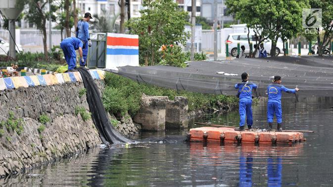 Petugas melepas kain waring atau jaring yang menutupi Kali Item di Kemayoran Jakarta, Rabu (14/11). Pelepasan waring yang sebagian dalam kondisi sudah robek itu dilakukan lantaran banyak warga yang membuang sampah di atasnya (Merdeka.com/Iqbal S. Nugroho)