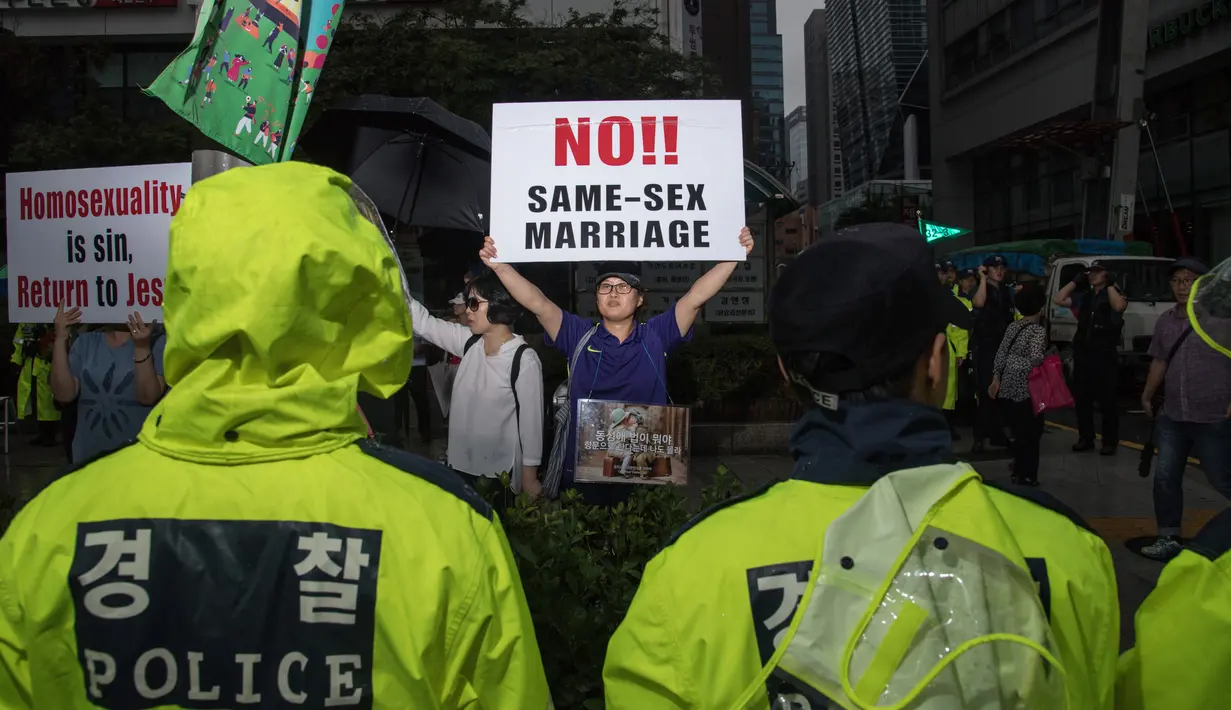 Warga menunjukan poster anti-gay saat acara parade 'Gay Pride' di Seoul, Korea Selatan (15/7). (AFP Photo/Ed Jones)