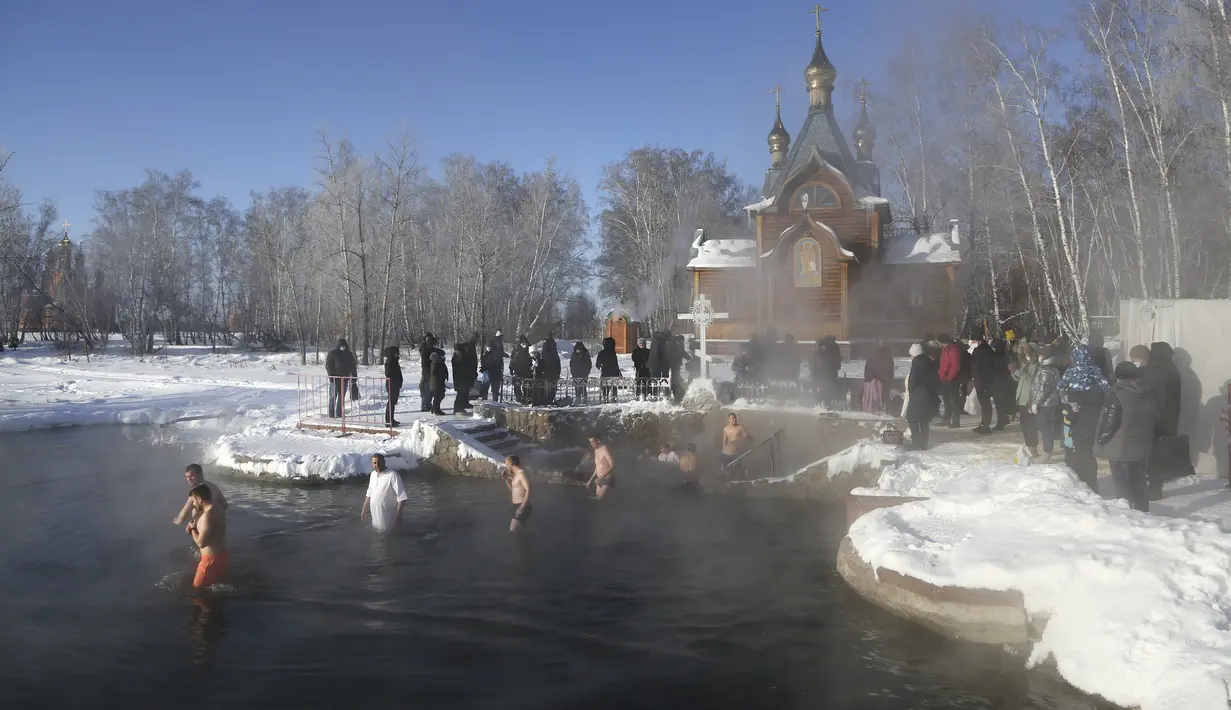 Orang-orang berjalan untuk mandi di air selama perayaan Epiphany tradisional karena suhu turun sekitar -24 derajat (-11,2 derajat Fahrenheit) di dekat biara Achairsky di luar kota Omsk di Siberia, Rusia (19/1/2021). (AP Photo/Evgeniy Sofiychuk)