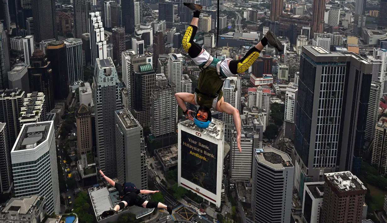 Penerjun Amerika Serikat Sean Devlin (kanan) melompat dari dek terbuka Menara Kuala Lumpur saat International Tower Jump, Kuala Lumpur, Malaysia, 3 Februari 2023. Lebih dari 100 penerjun melompat dari Menara Kuala Lumpur setinggi 300 meter yang terkenal tersebut. (MOHD RASFAN/AFP)