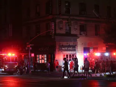 Pejalan kaki menyeberang jalan dekat kendaraan tanggap darurat saat pemadaman listrik di New York, AS, Sabtu (13/7/2019). Pemadaman listrik melanda sekitar 42 ribu pelanggan di Kota New York. (AP Photo/Michael Owens)