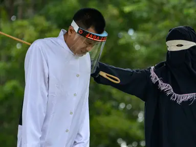 Salah seorang pasangan terpidana kasus zina (kiri) menjalani hukuman cambuk di Masjid Al Munawarah, Kota Jantho, Aceh Besar, Jumat (4/9/2020). Pasangan terpidana yang terbukti melanggar Syariat Islam dalam kasus zina itu masing masing menjalani sebanyak 100 cambuk. (CHAIDEER MAHYUDDIN/AFP)