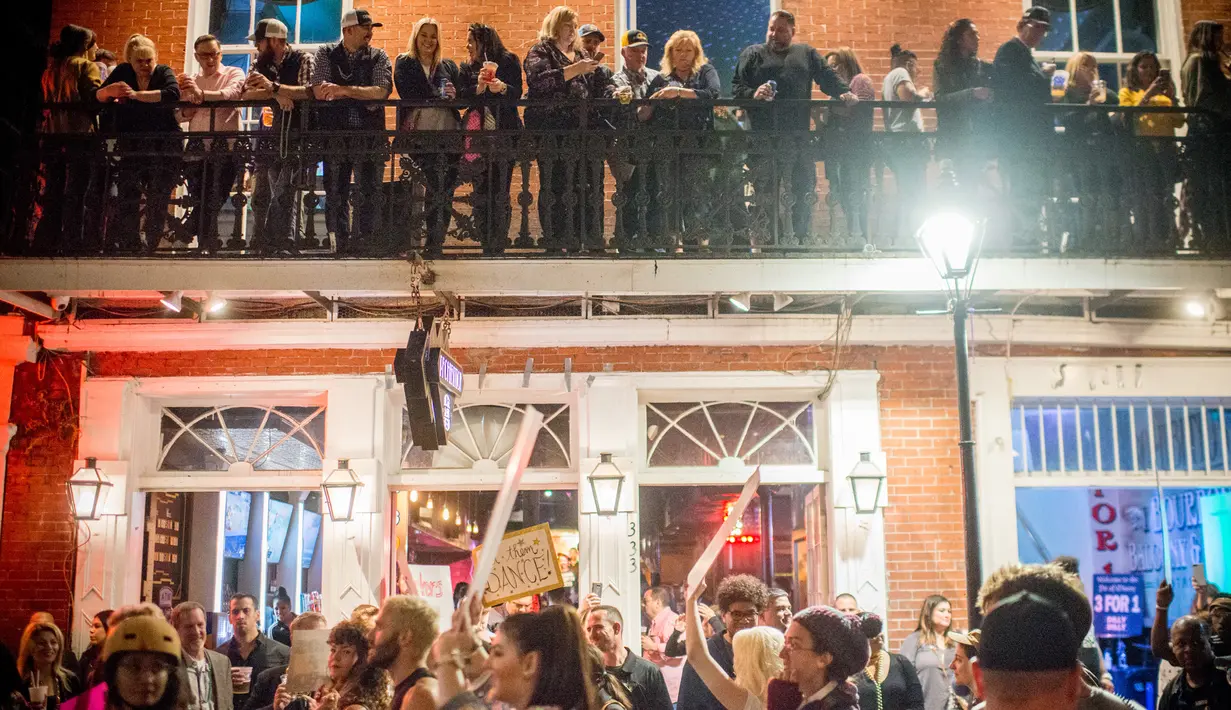 Warga melihat para demonstran yang sedang melakukan aksi di Bourbon Street, New Orleans (1/2). Sebelumnya delapan klub di New Orleans telah ditutup karena pelanggaran prostitusi dan narkoba. (AFP/Emily Kask)