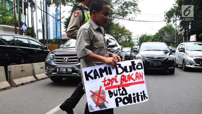 Seorang petugas polisi membantu penyandang disabilitas PASTI menyebrangi  jalan saat menggelar aksi di depan kantor Majelis Ulama Indonesia (MUI), Jakarta Pusat, Rabu (14/11). (Merdeka.com/Imam Buhori)