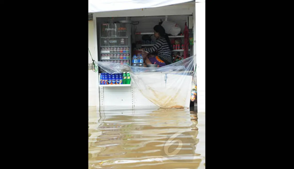 Pedagang menunggu surutnya air yang menggenangi warungnya di kawasan Grogol, Jakarta, Rabu (11/2). Hingga kini sejumlah kawasan di Jakarta masih tergenang banjir akibat dari hujan yang mengguyur  sejak Minggu (8/2). (Liputan6.com/Faisal R Syam)