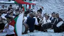 Sejumlah pria Bulgaria mengibarkan bendera sambil memainkan alat musik tradisional sambil menari di perairan sungai Tundzha selama Hari Epiphany di kota Kalofer, Bulgaria (6/1). (AP Photo/Valentina Petrova)
