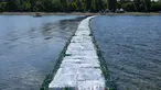Warga memeriksa jembatan apung dari botol plastik yang ditempatkan di Danau Ada Ciganlija di Beograd, Serbia, Kamis, 27 Juli 2023. (AP Photo/Darko Vojinovic)