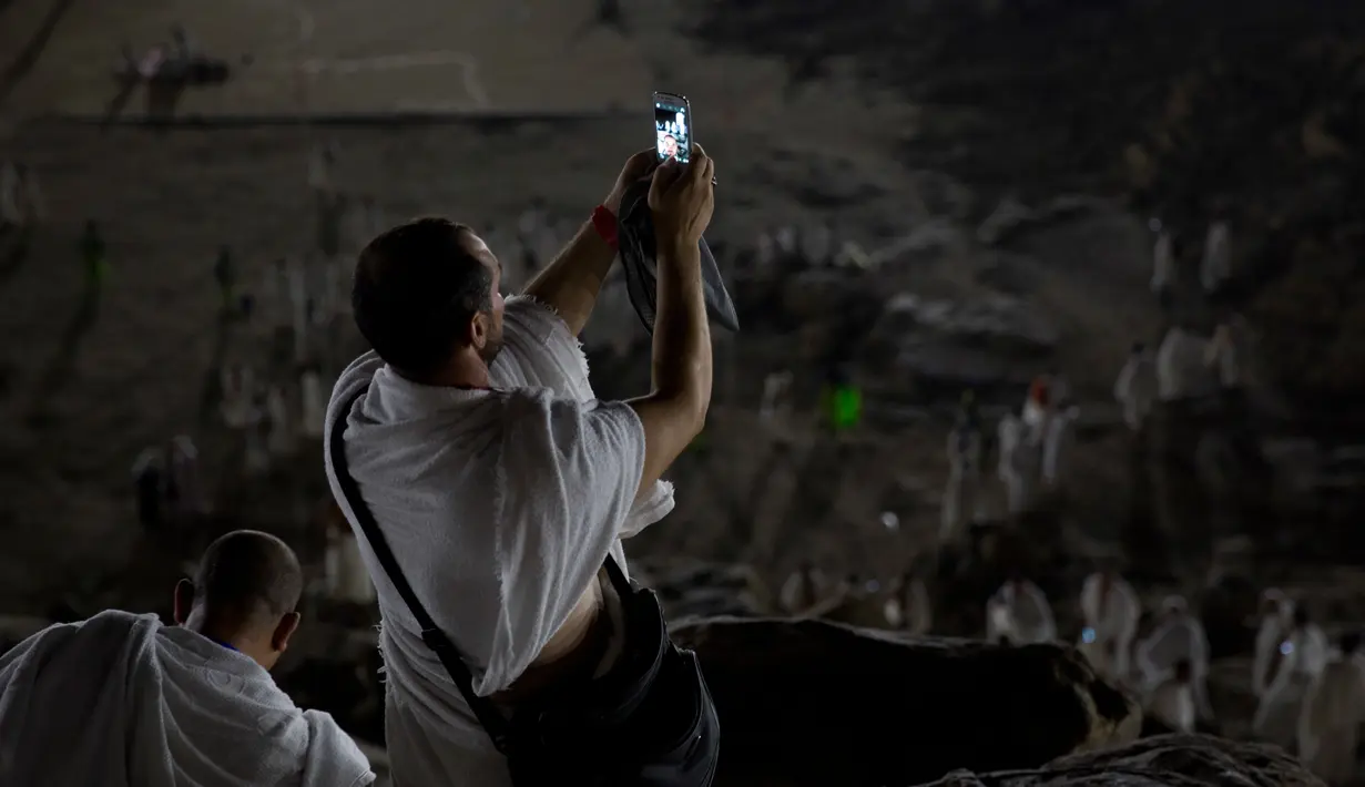 Jemaah calon haji berselfie saat berada di Bukit Jabal Rahmah saat mereka tiba di Arafah untuk menjalani wukuf di luar kota suci Mekah, Arab Saudi (30/8). Puncak ibadah haji ditandai dengan pelaksanaan wukuf di Arafah. (AP Photo / Khalil Hamra)