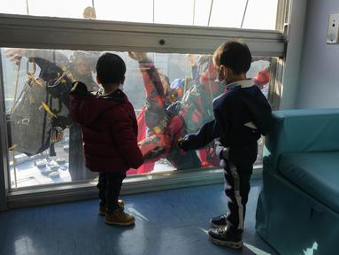 Dua orang berpakaian superhero turun dari atap untuk memberi kejutan di jendela kamar pasien anak di bangsal Pediatri rumah sakit San Paolo di Milan, Italia, Rabu (15/12/2021). Aksi Spiderman dan kawan-kawannya itu untuk menghibur anak-anak yang dirawat di rumah sakit tersebut. (AP Photo/Luca Bruno)