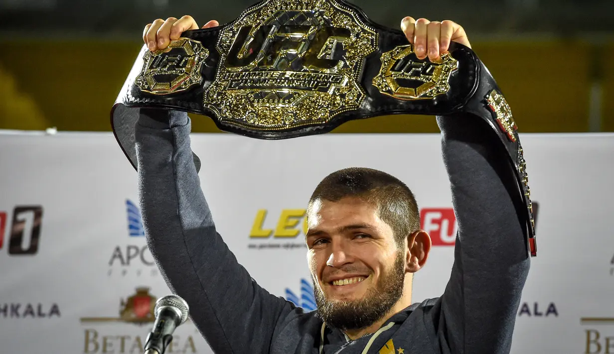 Juara kelas ringan UFC, Khabib Nurmagomedov mengangkat sabuk juaranya saat tiba di Makhachkala, Rusia, Senin (8/10). Khabib menjadi pusat perhatian dunia setelah sukses mempertahankan sabuk juara kelas ringan melawan Conor McGregor. (AFP/Vasily MAXIMOV)