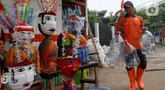 Petugas Unit Penanganan Sampah (UPS) Badan Air (BA) Dinas Lingkungan Hidup DKI Jakarta Kecamatan Jatinegara membuat ondel-ondel mini dari galon air minum bekas di Jakarta, Selasa (25/6/2024). (Liputan6.com/Herman Zakharia)