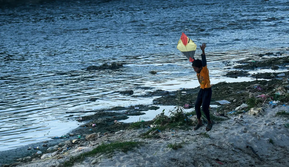 Seorang anak menerbangkan layang-layang di tepi sungai menjelang festival Hindu Dashain di Kathmandu (7/10/2020). Festival ini yang paling dinantikan di Nepal, Bhutan, Burma, dan perbukitan India Utara. (AFP/Prakash Mathema)