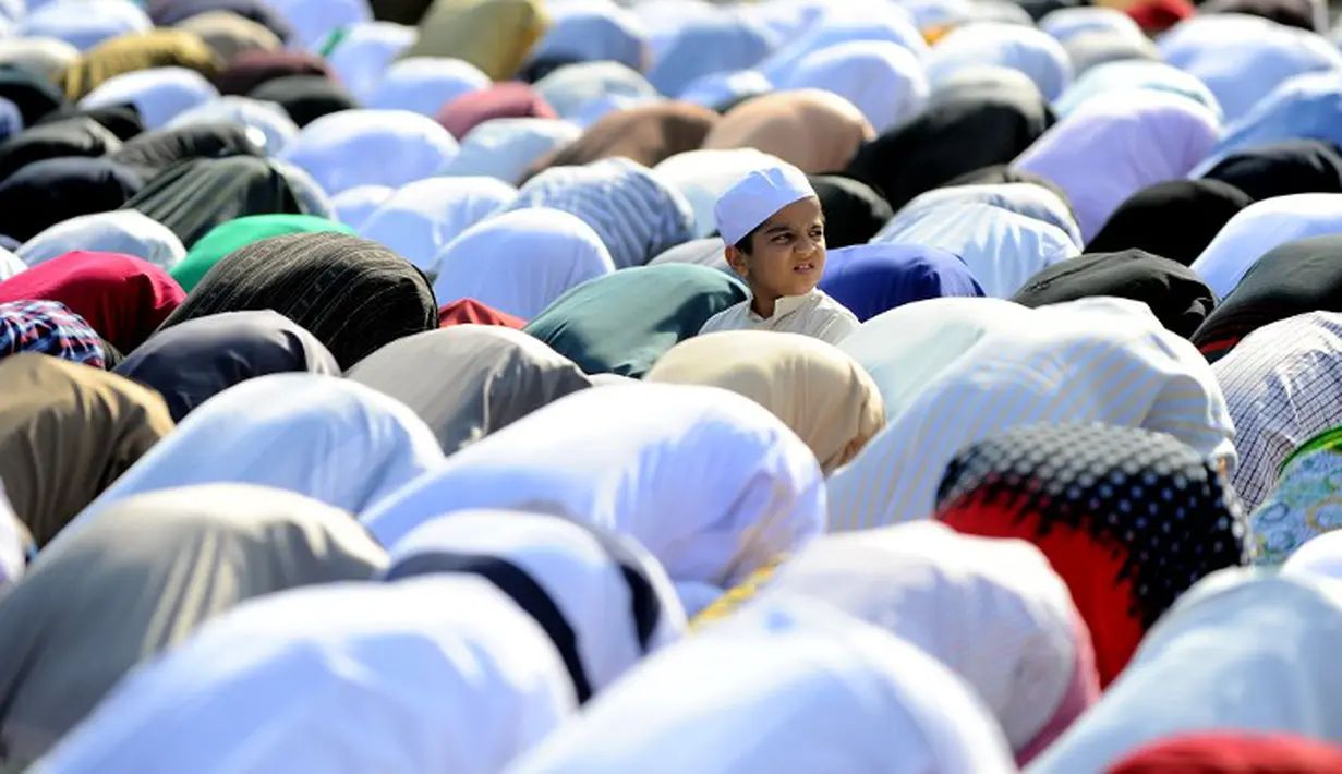 Seorang bocah malah asyik melihat sesuatu saat seluruh jamaah melakukan sujud, Hyderabad, India, Senin (6/10/2014) (AFP Photo/Noah SEELAM) 