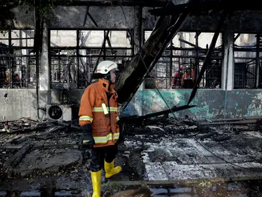 Petugas pemadam kebakaran mengamati sisa Stasiun Klender, Jakarta Timur yang terbakar, Jumat (19/5). Kebakaran yang terjadi sekitar 07.30 WIB di Stasiun Klender ini melalap kantor kepala stasiun hingga loket tiket. (Liputan6.com/Faizal Fanani)