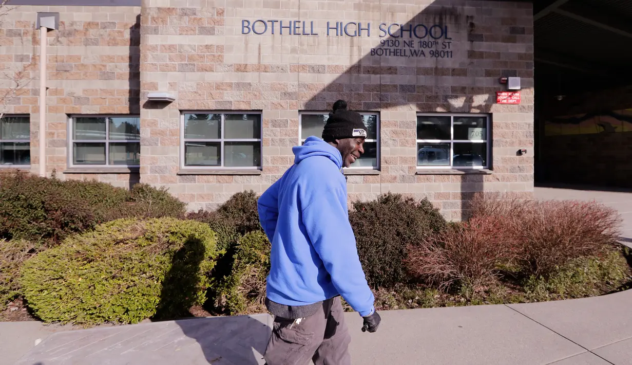 Petugas kebersihan berjalan menuju bagian depan Bothell High School yang ditutup di Bothell, Washington, Kamis (27/2/2020). Sekolah di pinggiran kota Seattle ditutup setelah  anggota keluarga seorang staf sekolah itu dikarantina karena menunjukkan gejala tertular virus corona. (AP/Elaine Thompson)