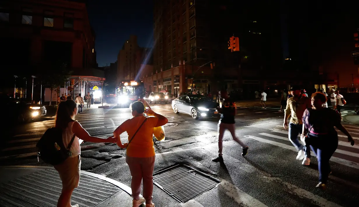 Pejalan kaki menyeberang jalan yang gelap saat terjadi pemadaman listrik di New York, AS, Sabtu (13/7/2019). Tidak ada keterangan mengenai pemadaman listrik yang terjadi di New York. (AP Photo/Michael Owens)