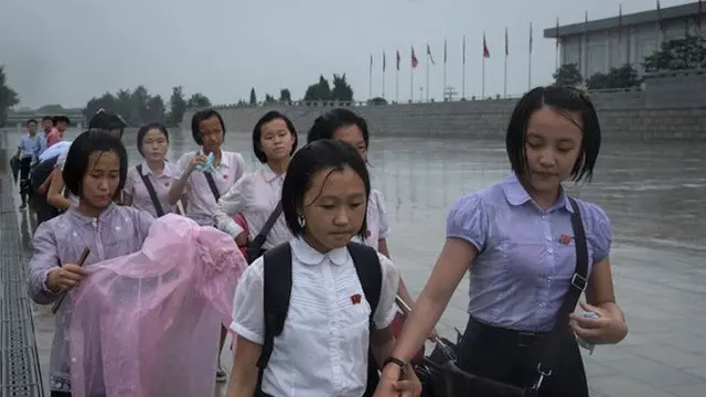 Para siswa tengah berjalan meski hujan deras untuk memberi penghormatan kepada mantan pemimpin Korea Utara Kim Il Sung dan Kim Jong-Il di luar Istana Kumsusan saat negara tersebut menandai 'Hari Kemenangan' di Pyongyang (AFP/Ed JONES)
