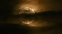Bulan terlihat melalui awan saat gerhana bulan sebagian di Srinagar, India, Jumat (5/5/2023). Gerhana Bulan Penumbra akan muncul pada Jumat (5/5/) hingga Sabtu (6/5) dinihari. (TAUSEEF MUSTAFA / AFP)
